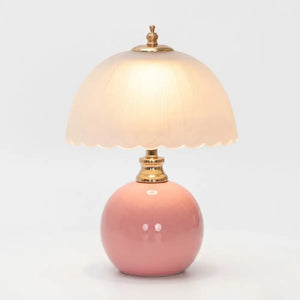 Luminária de mesa cogumelo rosa Radiantbr com cúpula de vidro fosco acesa com luz quente, isolada em fundo branco gelo.