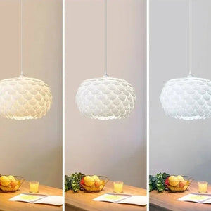 Montagem comparativa lado a lado da mesma Luminária Pendente Pétala acesa com três opções de lâmpada: luz branca quente (esquerda), luz neutra (centro) e luz branca fria (direita)