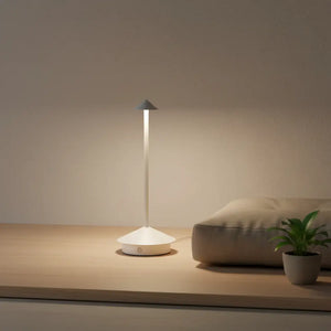 Luminária de mesa branca sobre uma base de madeira clara em um canto zen, com almofada e planta pequena, ideal para meditação e relaxamento