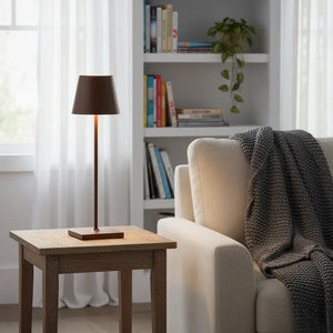 Luminária de mesa de design marrom em uma sala de estar aconchegante. A iluminação portátil e recarregável é perfeita para um canto de leitura confortável
