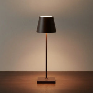 Luminária de mesa de design marrom sobre uma mesa de madeira. A luminária LED portátil e recarregável cria um ambiente elegante e moderno