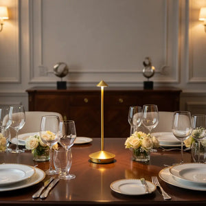 Luminária de mesa dourada como peça central de uma mesa de jantar elegante, com louças finas e taças de cristal, criando uma atmosfera de celebração