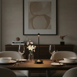 Luminária de mesa minimalista preta usada para iluminar uma mesa de jantar, criando uma atmosfera sofisticada e aconchegante.