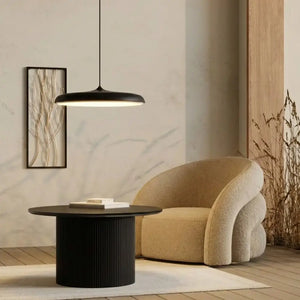 Decoração de sala de estar estilo Japandi com Pendente Macaron Preto suspenso baixo sobre mesa lateral, criando um canto de leitura aconchegante junto à poltrona.