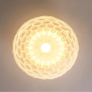 Vista inferior da Luminária Pendente Pétala acesa, mostrando a estrutura orgânica em camadas e o efeito de luz difusa central sem ofuscamento