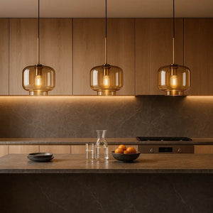 Trio de luminárias pendentes Radiantbr Auro em vidro âmbar e dourado instaladas sobre bancada de cozinha planejada