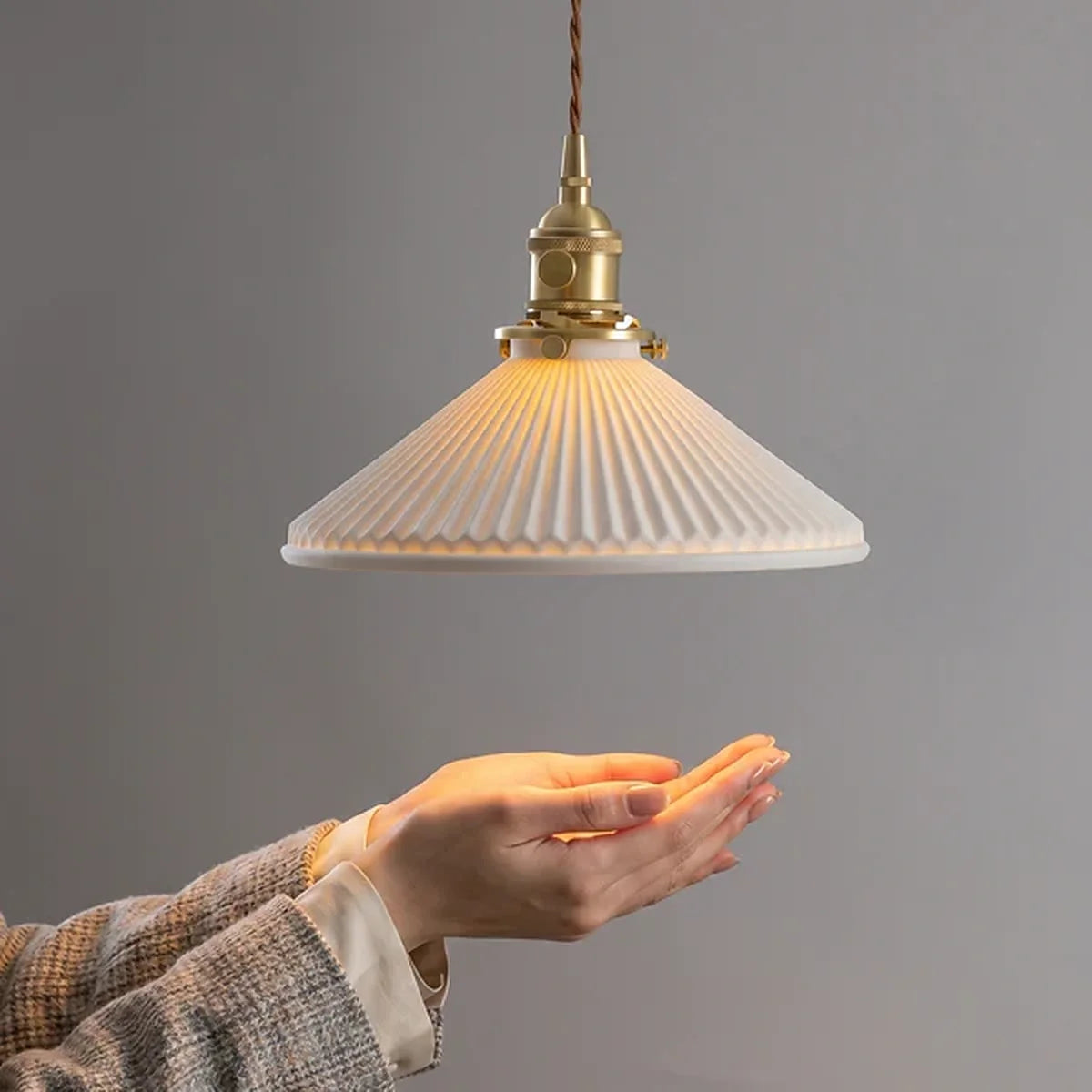 Luminária Pendente Kiyo acesa com escala visual próxima à mão