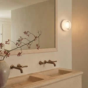 Arandela de Parede Redonda LED Toth Branca acesa em banheiro com decoração bege clean 
