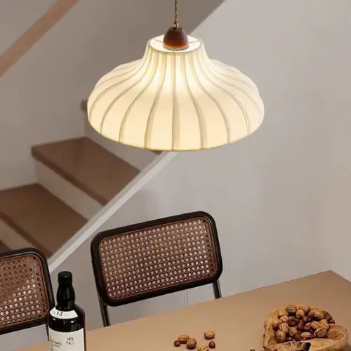 Luminaria Pendente Moderno Minimalista Madeira Tecido Radiant sobre Mesa de canto com cadeira rattan + escadaria — composição relaxada, luz quente
