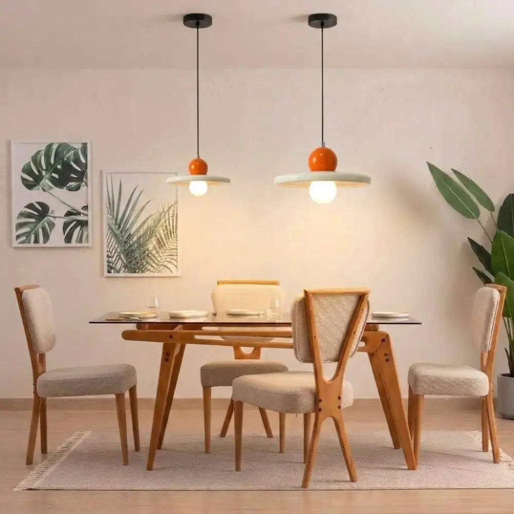 Composição decorativa com dois lustres pendentes estilo francês minimalista na cor laranja, tamanhos 20cm e 30cm, instalados lado a lado sobre uma mesa de jantar
