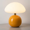 Abajur cogumelo laranja moderno em um fundo claro, destacando a base de cerâmica brilhante e a cúpula branca difusa. Abajur de mesa de design com estilo e personalidade