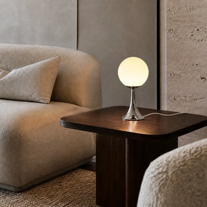 Abajur Globo Luma em sala com luz neutra, mesa lateral escura e cabo branco visível