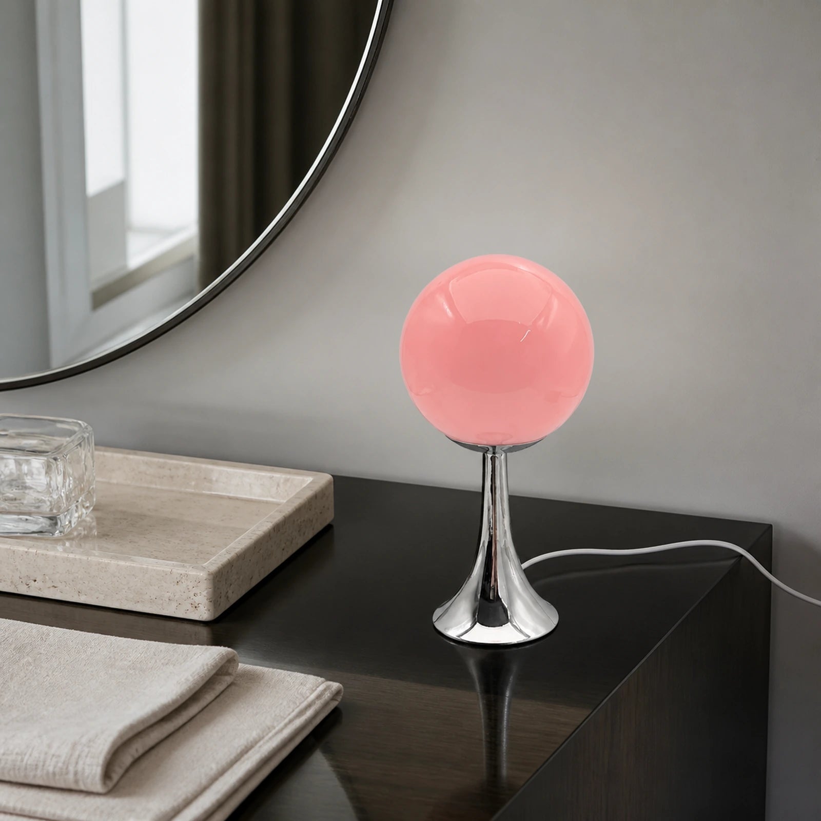 Abajur Globo Mika em console escuro com espelho, luz neutra e cabo branco visível