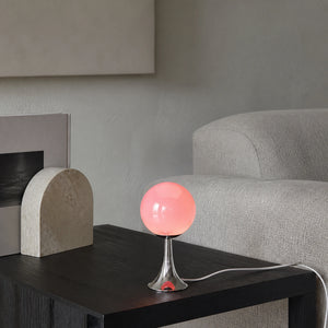 Abajur Globo Mika em sala com luz neutra, mesa escura e cabo branco visível