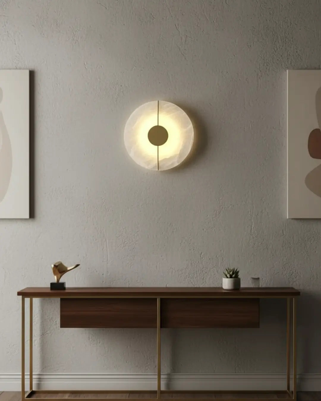 Arandela moderna circular com luz difusa e detalhes dourados, instalada em uma parede de cimento queimado em um hall de entrada elegante. A luminária de parede de design cria um efeito de luz suave e contemporâneo sobre um aparador de madeira e metal