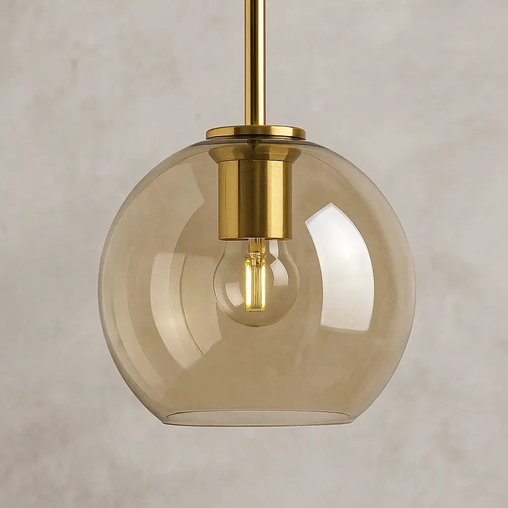 Detalhe do pendente globo âmbar dourado com vidro soprado translúcido e lâmpada LED em soquete dourado refinado.