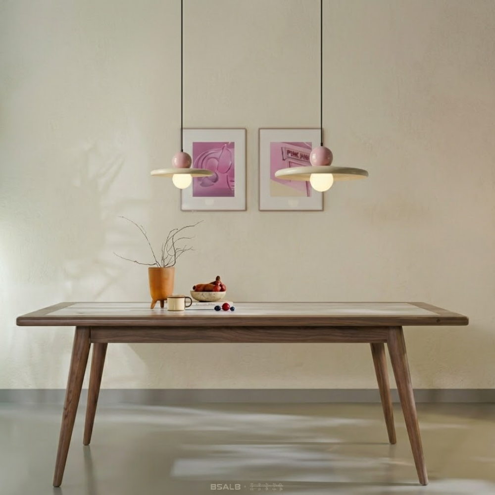 Composição de iluminação com dois lustres pendentes estilo francês minimalista na cor rosa, tamanhos 20cm e 30cm, acesos sobre uma mesa de jantar contemporânea