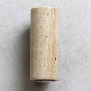 Close-up focado na textura natural e porosidade da pedra mármore travertino da arandela Siena