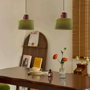 Sala de jantar com mesa de madeira escura decorada com uma dupla de Pendentes Nordic em vidro Verde, combinando estilo retrô e moderno