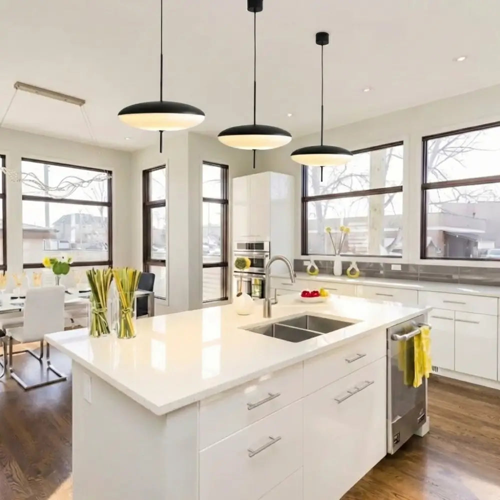 Cozinha planejada moderna com ilha central branca, decorada com um trio de Luminárias Pendente Disco UFO Pretas instaladas alinhadas sobre a bancada gourmet