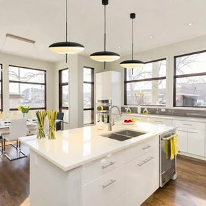 Cozinha planejada moderna com ilha central branca, decorada com um trio de Luminárias Pendente Disco UFO Pretas instaladas alinhadas sobre a bancada gourmet