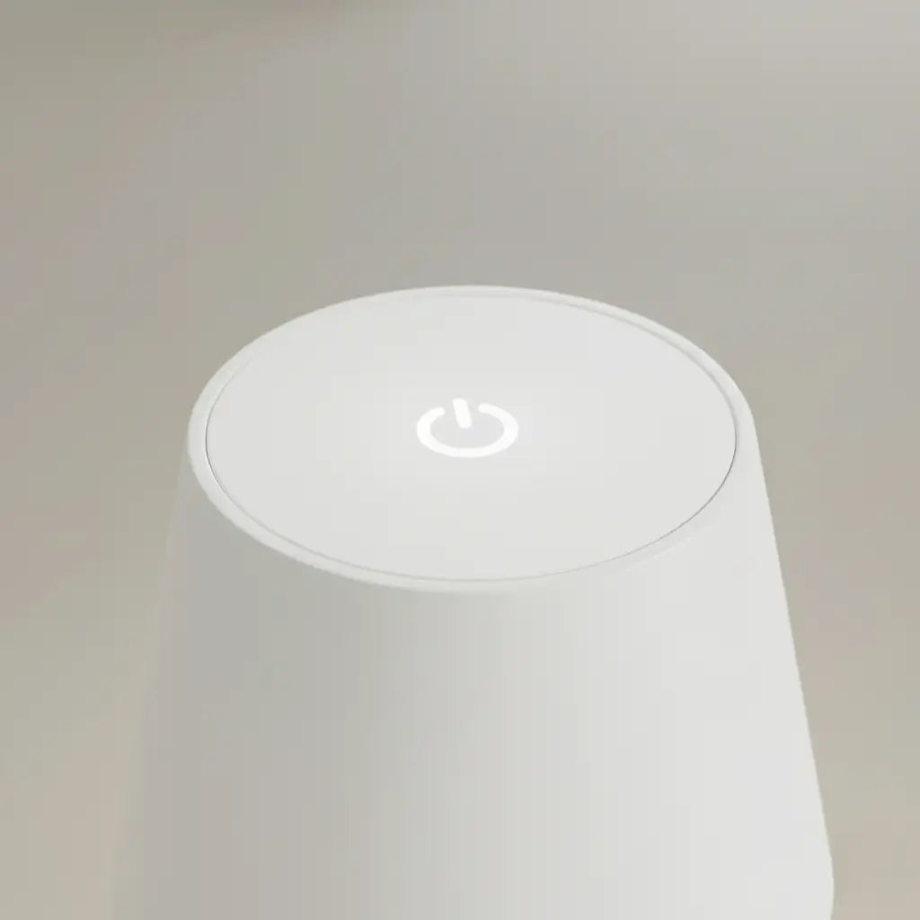 -up da parte superior da luminária de mesa branca, mostrando o botão de toque retroiluminado para ligar/desligar e controlar a intensidade da luz