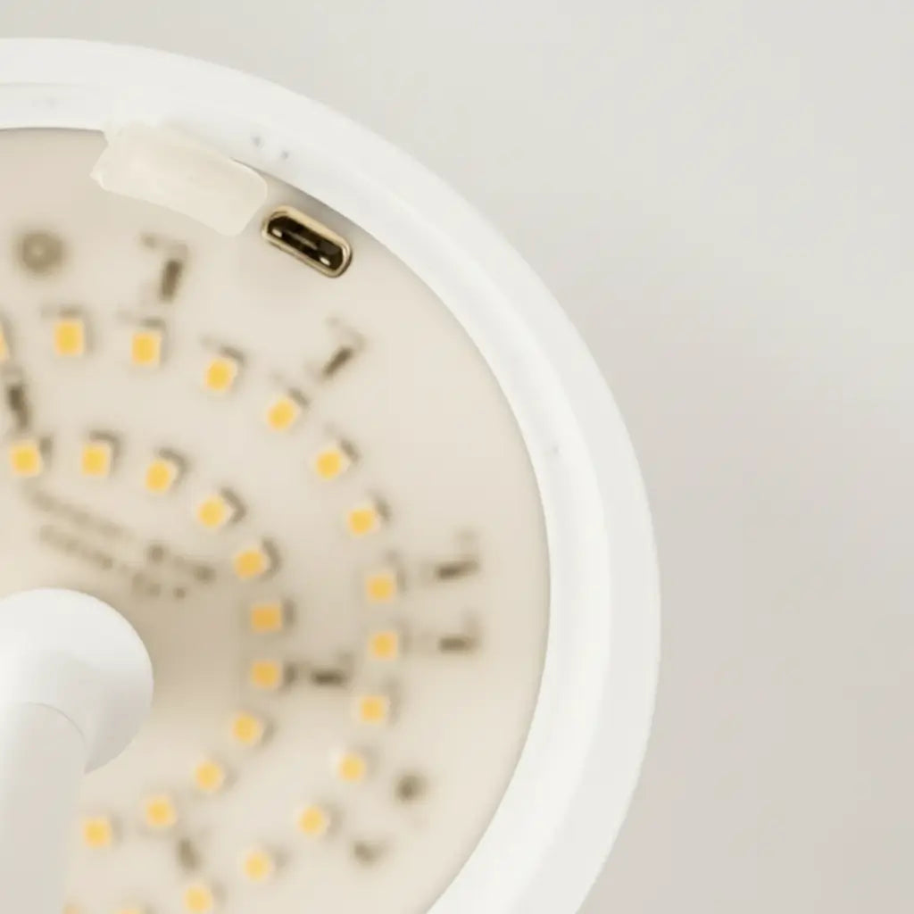 Vista técnica da parte interna da luminária de mesa branca, mostrando a tecnologia LED de alta performance e a porta de carregamento USB oculta