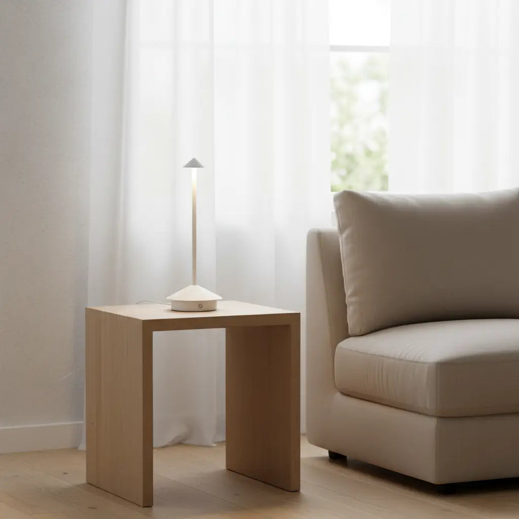 Luminária de mesa portátil branca em uma sala de estar minimalista com tons claros, cortinas leves e sofá bege, proporcionando iluminação suave e discreta