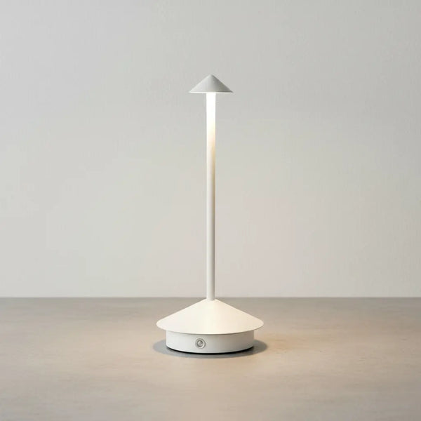 Luminária de mesa portátil sem fio na cor branca, com luz LED acesa, sobre uma superfície de concreto clara e elegante, em um fundo branco texturizado. Design clean e moderno
