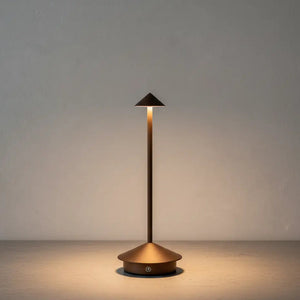 Luminária de mesa portátil sem fio na cor marrom, com luz LED acesa, sobre uma base de concreto texturizada