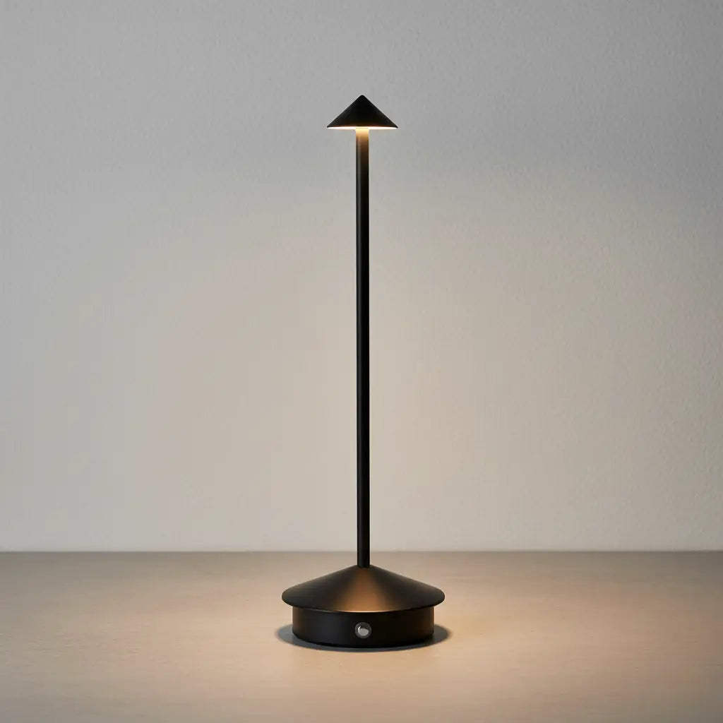 Luminária de mesa portátil sem fio na cor preta fosca, com luz LED acesa, sobre uma base de cimento minimalista. Design moderno e elegante