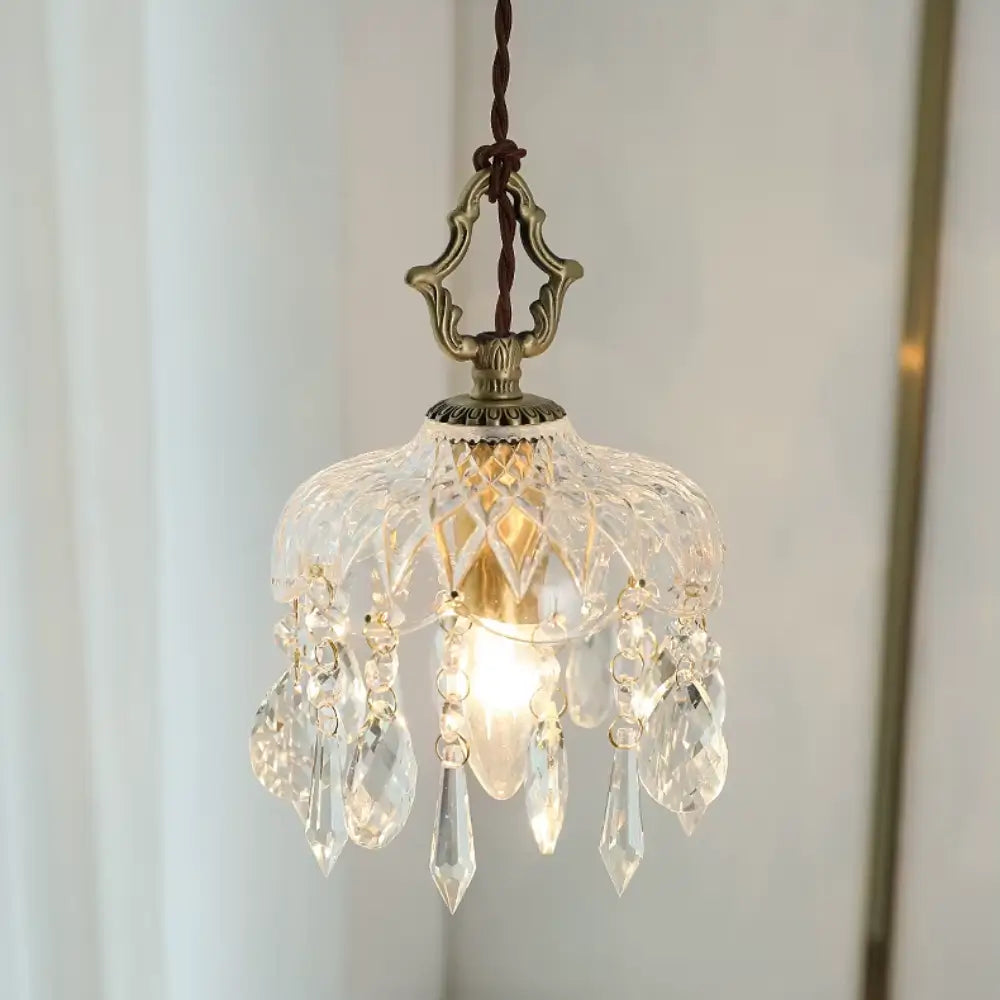 Luminária pendente de vidro facetado tipo cristal Marquise da Radiantbr acesa com luz quente, destacando os pingentes em gota contra um fundo claro com cortina branca.