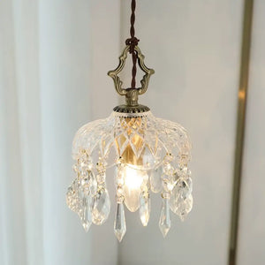 Luminária pendente de vidro facetado tipo cristal Marquise da Radiantbr acesa com luz quente, destacando os pingentes em gota contra um fundo claro com cortina branca.