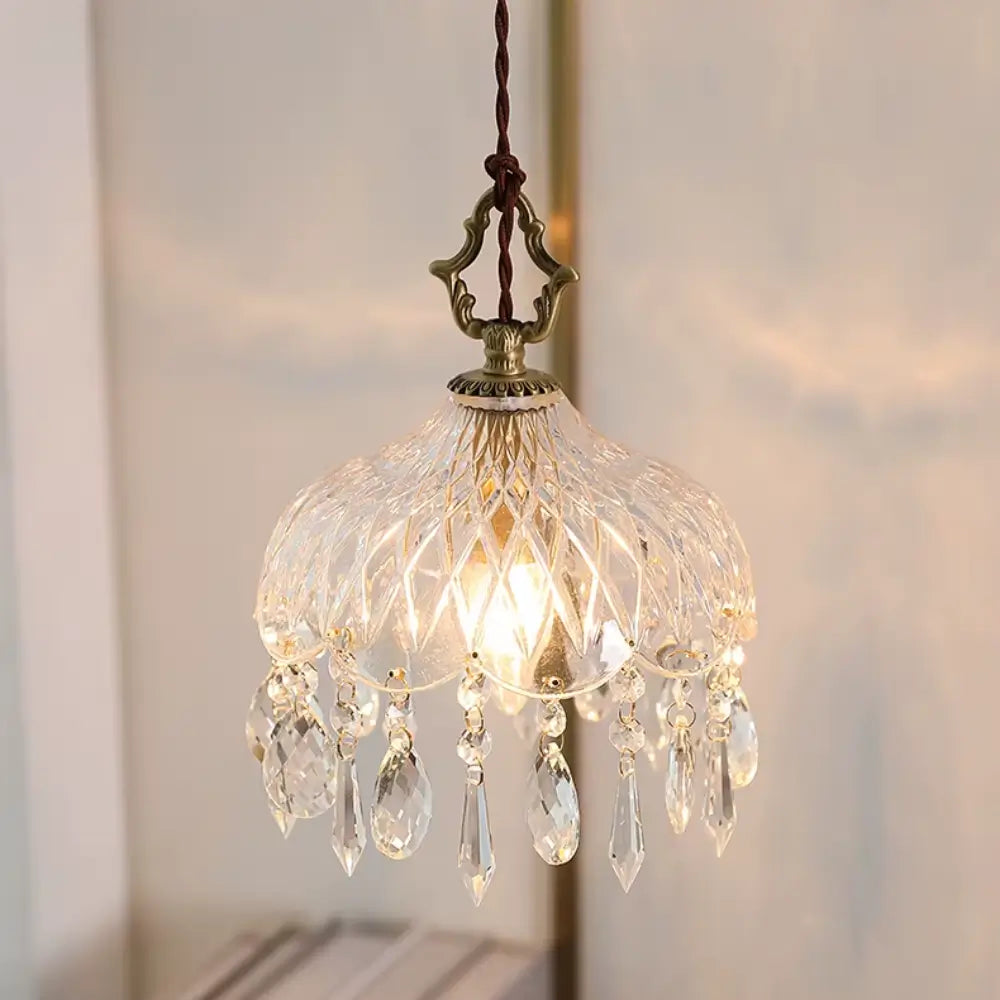 Luminária pendente de vidro facetado tipo cristal Marquise da Radiantbr acesa, exibindo pingentes em formato de gota e estrutura ornamentada em dourado polido.