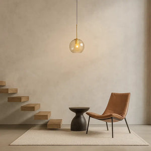 Luminária pendente globo âmbar dourado em hall minimalista, iluminação elegante em projeto arquitetônico contemporâneo.