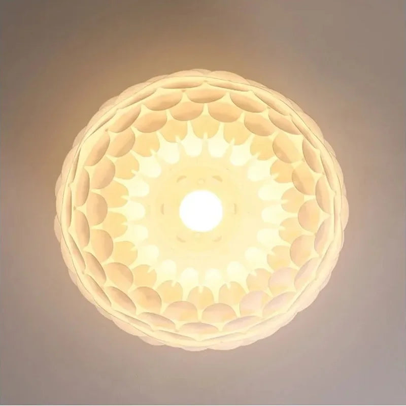 Vista inferior da Luminária Pendente Pétala acesa, mostrando a estrutura orgânica em camadas e o efeito de luz difusa central sem ofuscamento