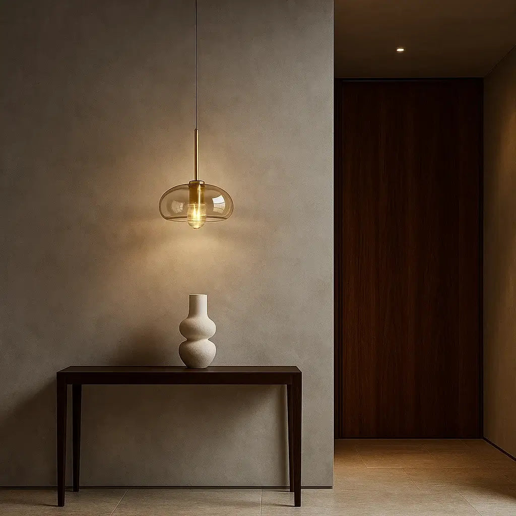 Pendente de vidro âmbar dourado iluminando hall de entrada sofisticado com parede em cimento queimado